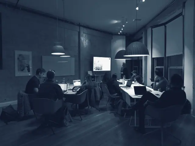 Un grup treballa amb portàtils en una sala de formació, amb una pantalla al fons