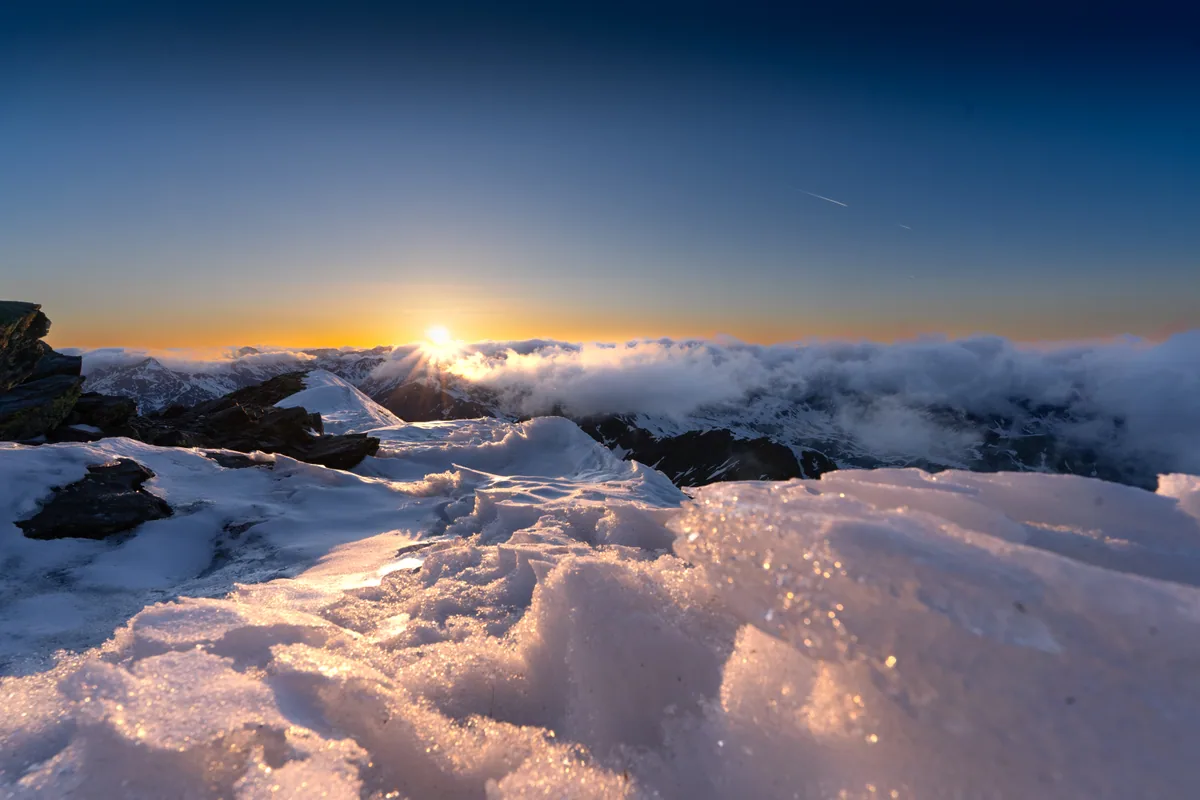 Le soleil se lève sur la neige gelée et une mer de nuages.